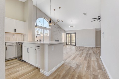 A kitchen with white cabinets and a wooden floor.