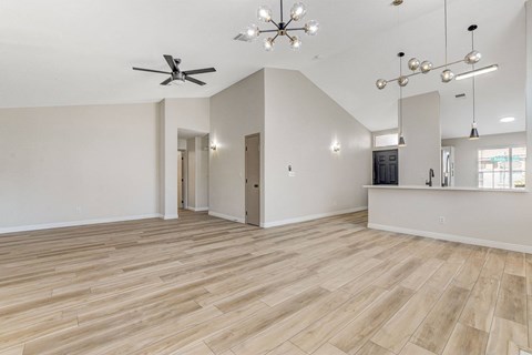 A spacious room with wooden flooring and a ceiling fan.