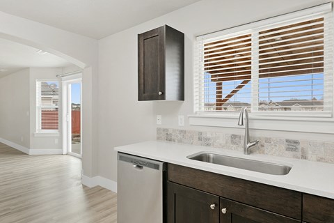 A kitchen with a sink and a window with blinds.