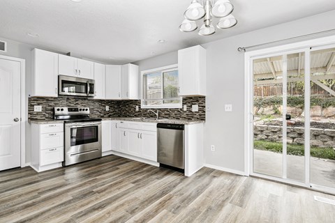 A kitchen with white cabinets and a stone backsplash.