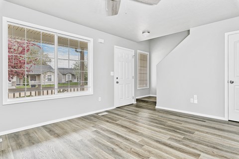 A room with a window showing a view of a house and trees.