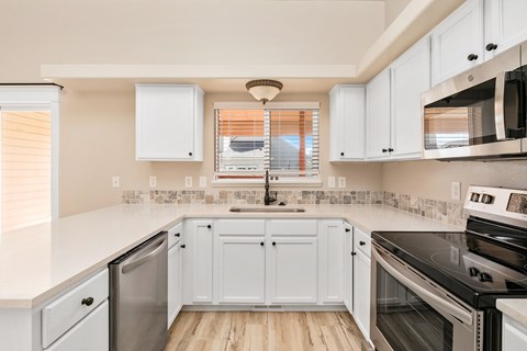A kitchen with white cabinets and appliances.
