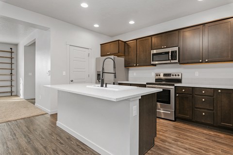 A modern kitchen with dark brown cabinets and white countertops.