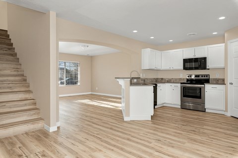 A spacious kitchen with white cabinets and a stainless steel oven.