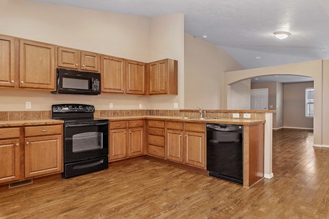 A kitchen with wooden cabinets and black appliances.