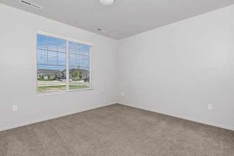 A room with a window showing a view of houses and trees.