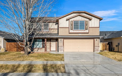 A house with a brown garage door and a tree in front.