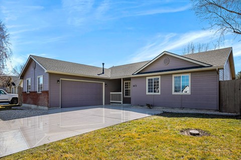 A house with a grey garage door and a brown fence.