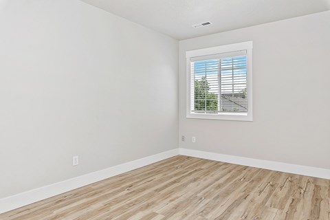 A room with a window and wooden flooring.