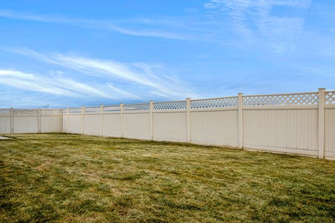 A long white fence runs along a grassy field.
