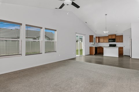 A spacious living room with a ceiling fan and large windows.