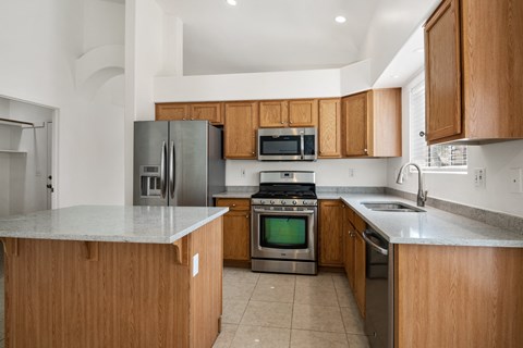 an empty kitchen with wooden cabinets and stainless steel appliances