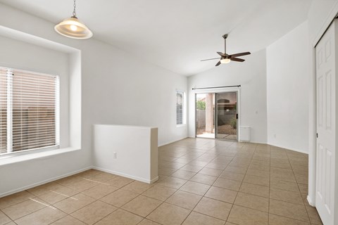 an empty living room with a ceiling fan and a tiled floor
