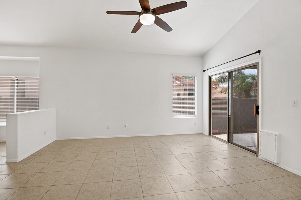 an empty living room with a ceiling fan and a sliding glass door