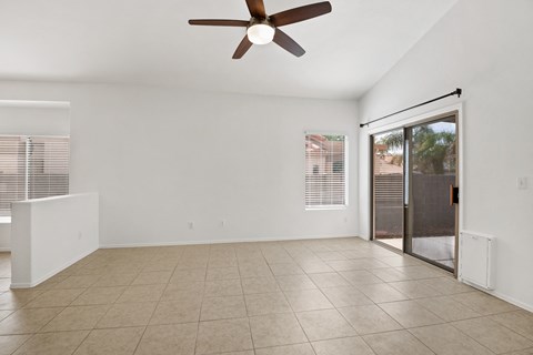 an empty living room with a ceiling fan and a sliding glass door