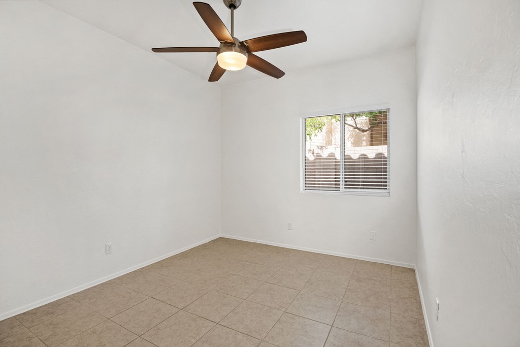 an empty living room with a ceiling fan and a tiled floor