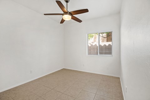 an empty living room with a ceiling fan and a tiled floor
