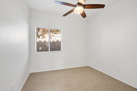 an empty room with a ceiling fan and a window