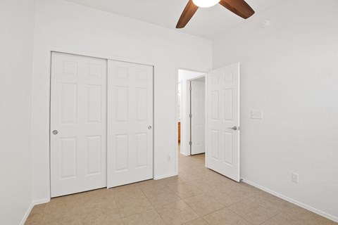 an empty living room with white doors and a ceiling fan