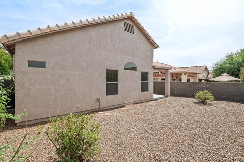 the side of a house with gravel and a driveway