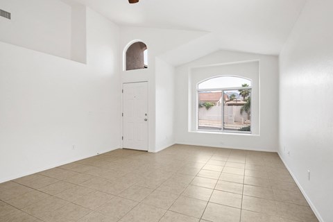 an empty living room with a large window and a tiled floor
