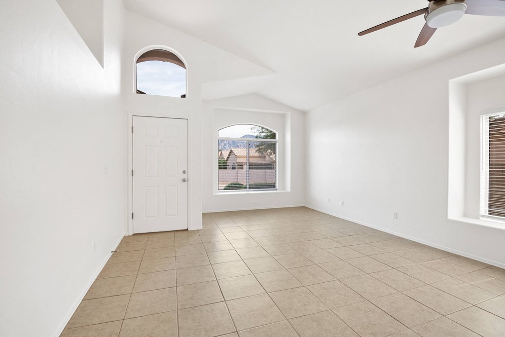 an empty living room with a ceiling fan and a window