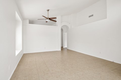 an empty living room with white walls and a ceiling fan