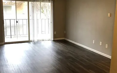 A room with a sliding glass door and wood flooring.