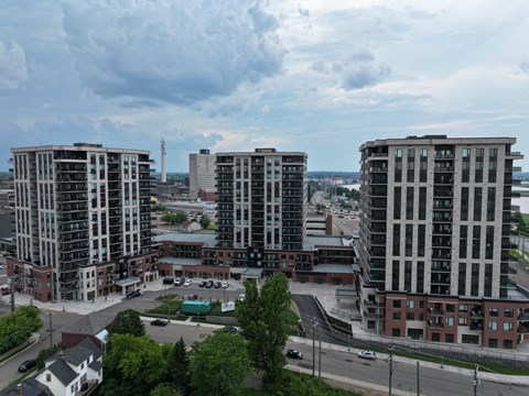 A cityscape with three tall buildings in the foreground and a cloudy sky above.