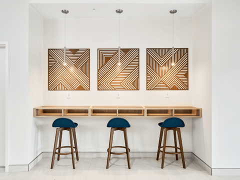 A bar with three stools and three hanging lights.
