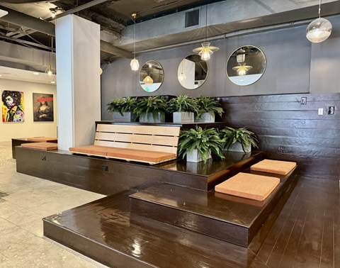 the lobby of a restaurant with wooden benches and potted plants