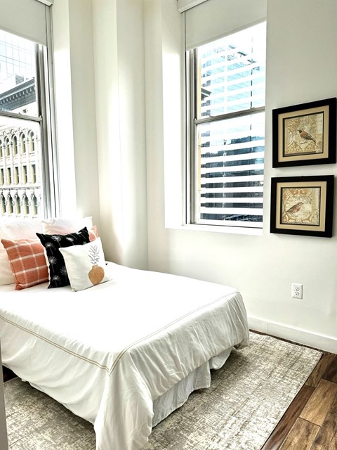 a bedroom with a white bed and two windows