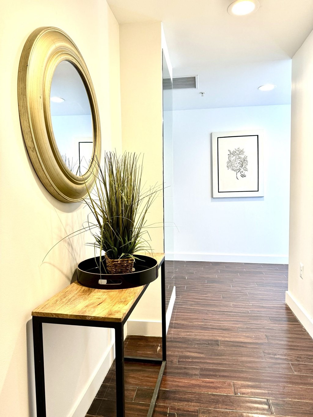a hallway with a mirror and a table with a plant