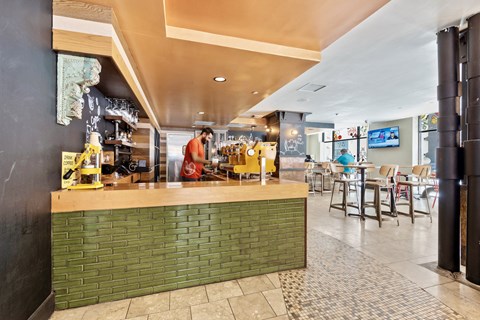the bar area of a restaurant with a worker at the counter