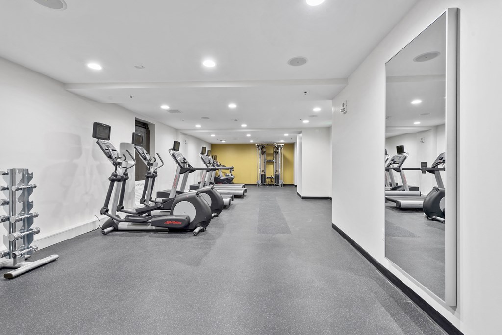 the gym has treadmills and other exercise equipment in a large room with white