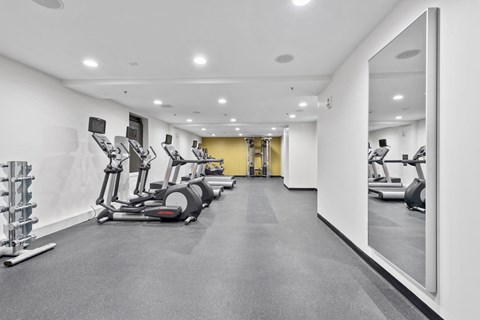 the gym has treadmills and other exercise equipment in a large room with white