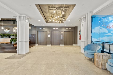 the lobby of a hotel lobby with blue chairs and a blue wall mural