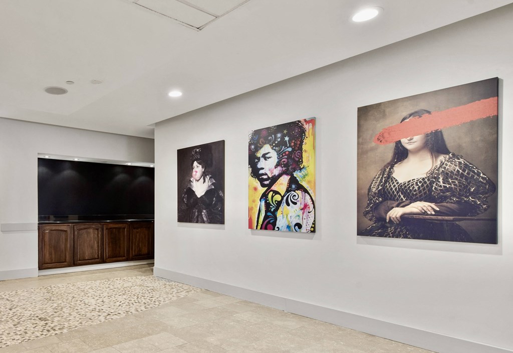 three paintings on a wall in a room with a tv