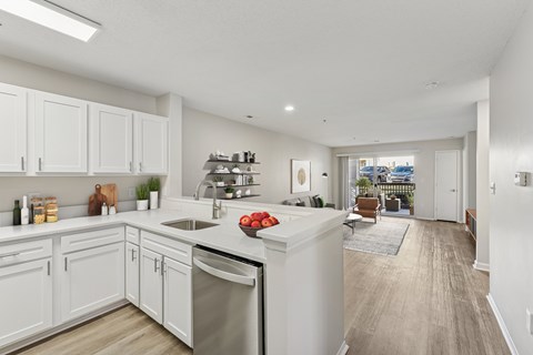 A kitchen with white cabinets and a wooden floor.