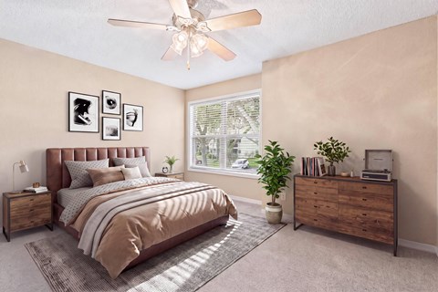 A bedroom with a bed, nightstand, and a window with a view of trees.