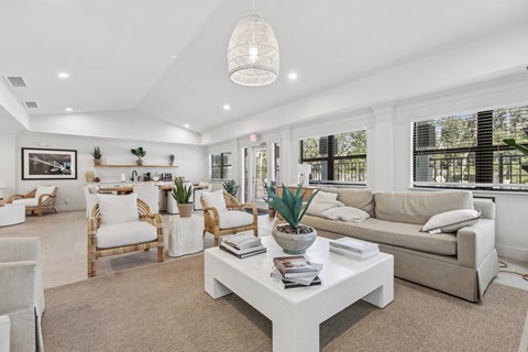 A well-lit, spacious living room with a white coffee table and beige sofa.