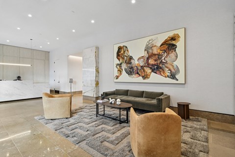 A large abstract painting hangs above a grey couch in a spacious room.