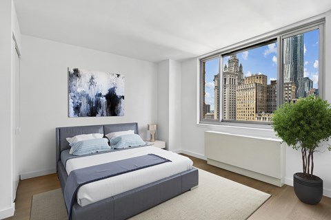 A bedroom with a large bed and a city view through the window.