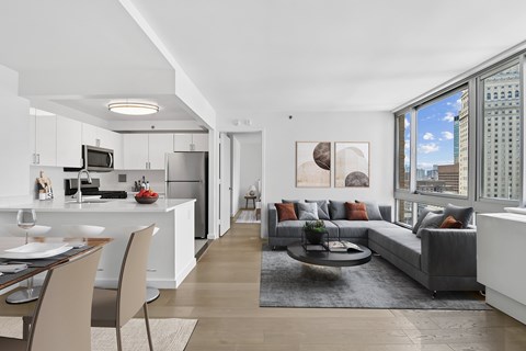 A modern living room with a grey couch and a dining table.
