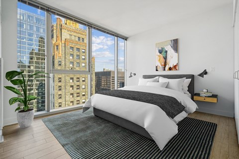 a bedroom with a large window and a bed and a rug