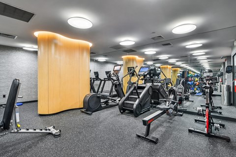 A gym with a variety of equipment including treadmills, weights, and exercise machines.