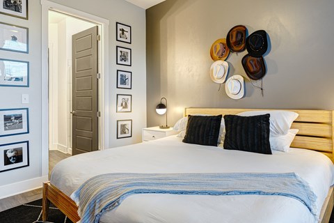 a bedroom with a bed and various hats on the wall