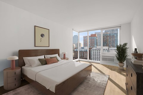 A bedroom with a large bed and a city view through the window.