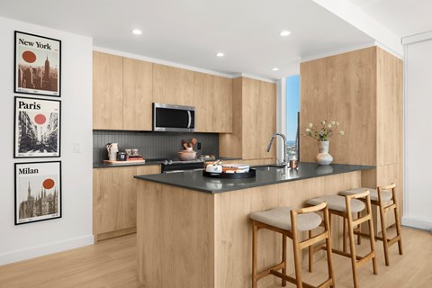 A kitchen with a bar area and three framed pictures on the wall.