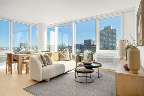 A living room with a couch, a table, and a view of the city.